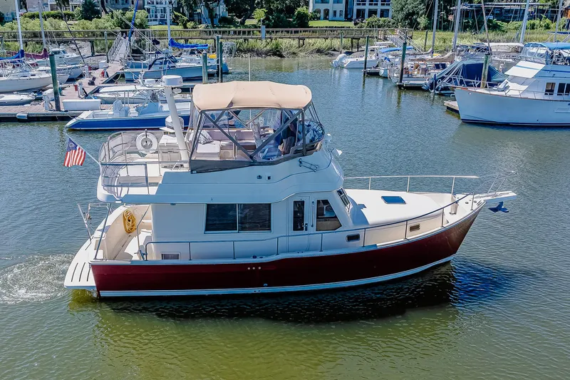 Coastal Fogg Yacht Photos Pics 2006 Mainship 34 Trawler cruising in a marina, featuring a red hull and flybridge.