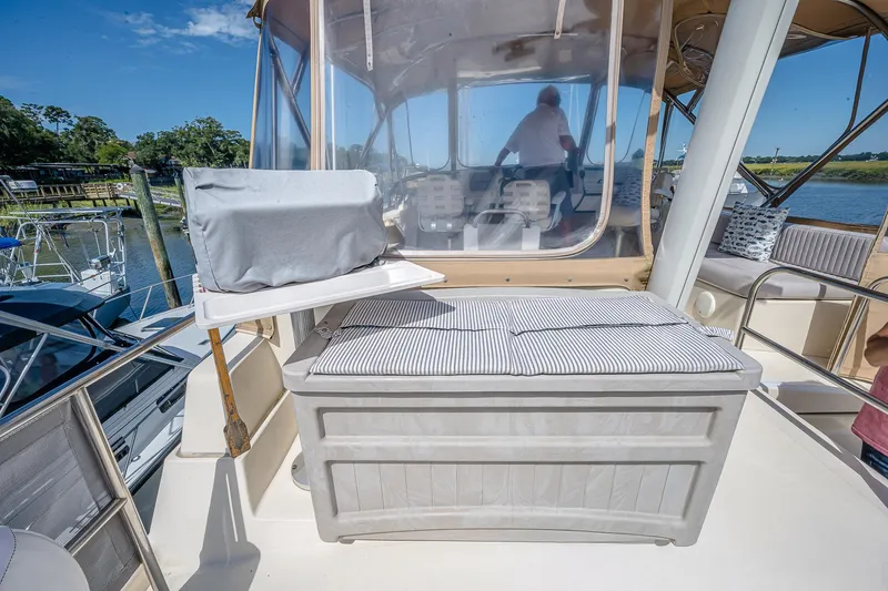Coastal Fogg Yacht Photos Pics 2006 Mainship 34 Trawler deck with seating and covered equipment, docked by the water.