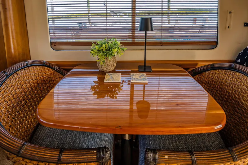 Coastal Fogg Yacht Photos Pics Cozy dining area on 2006 Mainship 34 Trawler with wooden table, wicker chairs, and decor.