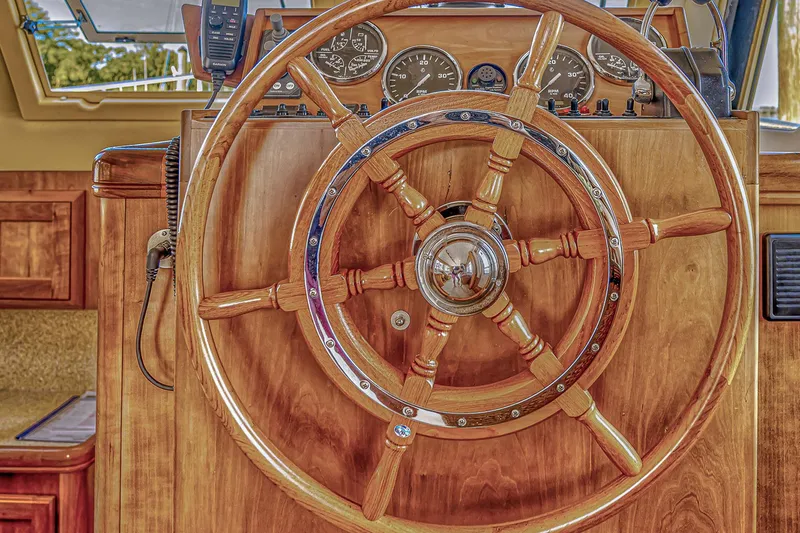 Coastal Fogg Yacht Photos Pics Wooden steering wheel of a 2006 Mainship 34 Trawler boat, featuring classic nautical design.
