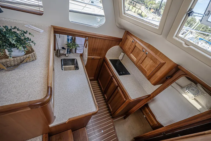 Coastal Fogg Yacht Photos Pics 2006 Mainship 34 Trawler interior with compact kitchen, wooden cabinetry, and cozy sleeping area.
