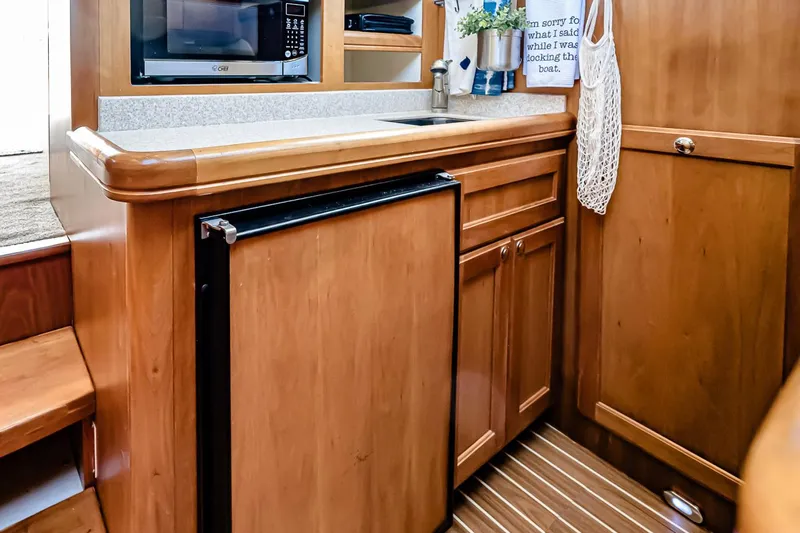 Coastal Fogg Yacht Photos Pics 2006 Mainship 34 Trawler kitchen with wooden cabinetry, microwave, and compact fridge.