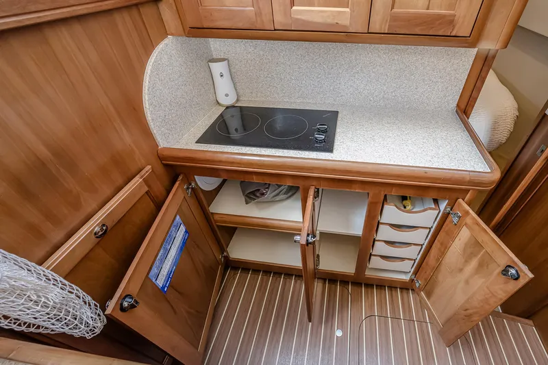 Coastal Fogg Yacht Photos Pics 2006 Mainship 34 Trawler kitchen with stove, open cabinets, and wood finish.