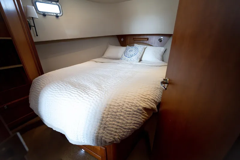 Coastal Fogg Yacht Photos Pics Cozy bedroom in 2006 Mainship 34 Trawler with white bedding and wooden accents.