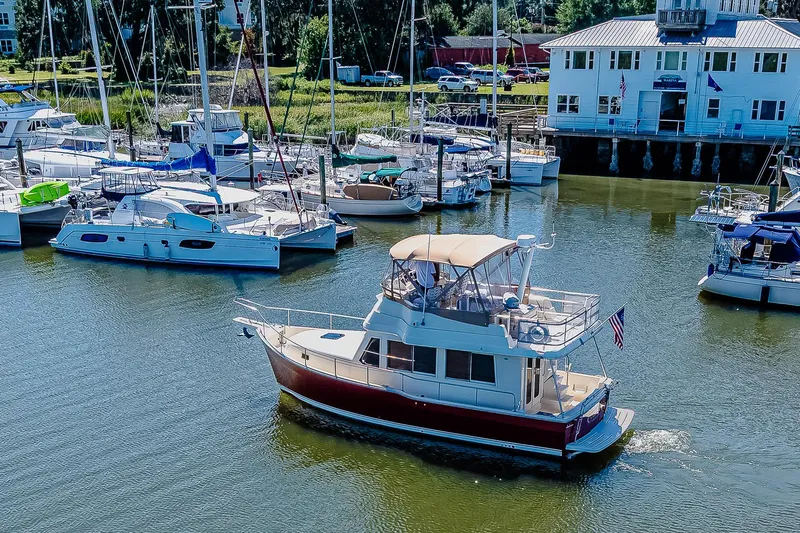 Coastal Fogg Yacht Photos Pics 2006 Mainship 34 Trawler cruising in a marina with docked boats.