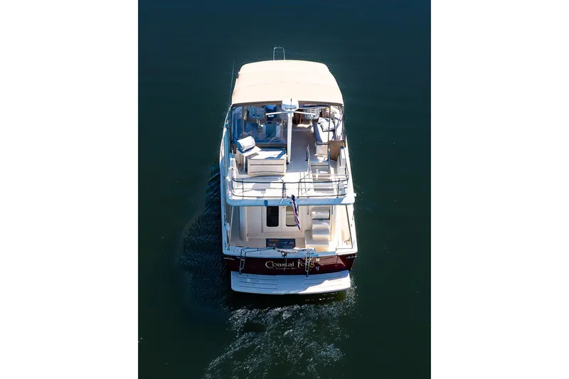 Coastal Fogg Yacht Photos Pics 2006 Mainship 34 Trawler cruising on calm water, aerial rear view.