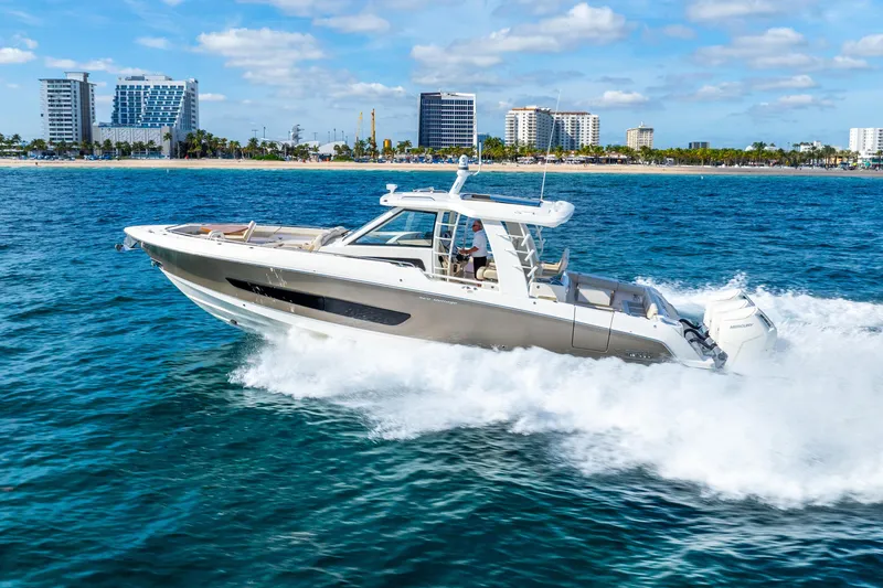 Gugui Yacht Photos Pics 2024 Boston Whaler 420 Outrage cruising on ocean near city skyline.