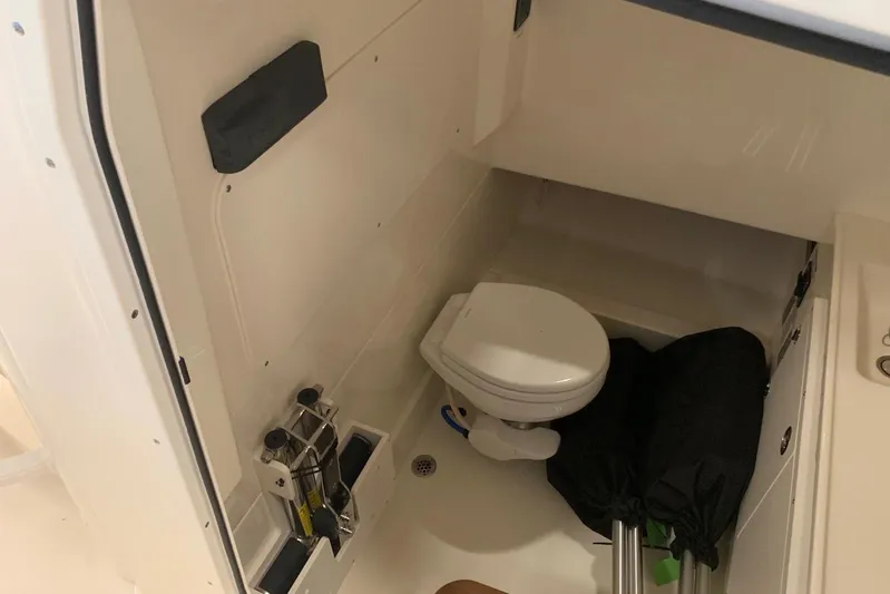  Yacht Photos Pics 2019 Boston Whaler 330 Outrage boat interior with compact marine toilet and storage area.