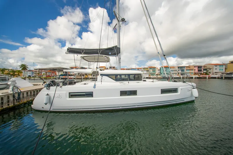 Dakiti Yacht Photos Pics 2023 Lagoon 46 catamaran docked in a marina with colorful buildings.