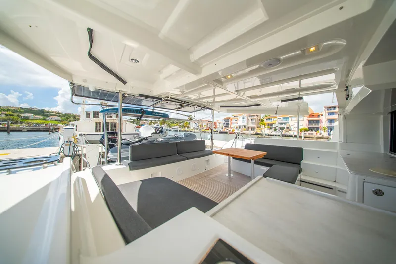 Dakiti Yacht Photos Pics Spacious interior of 2023 Lagoon 46 catamaran docked at marina, featuring modern seating and table.