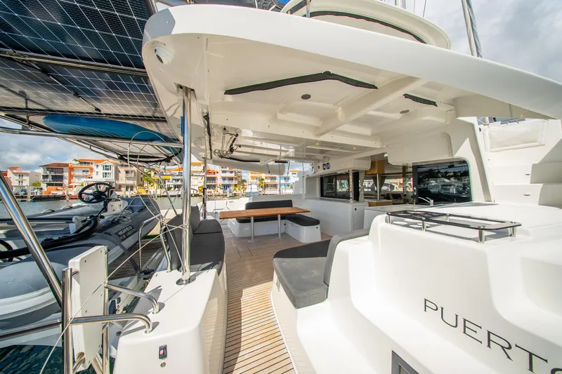 Dakiti Yacht Photos Pics 2023 Lagoon 46 catamaran with spacious deck, solar panels, and modern seating in a marina setting.