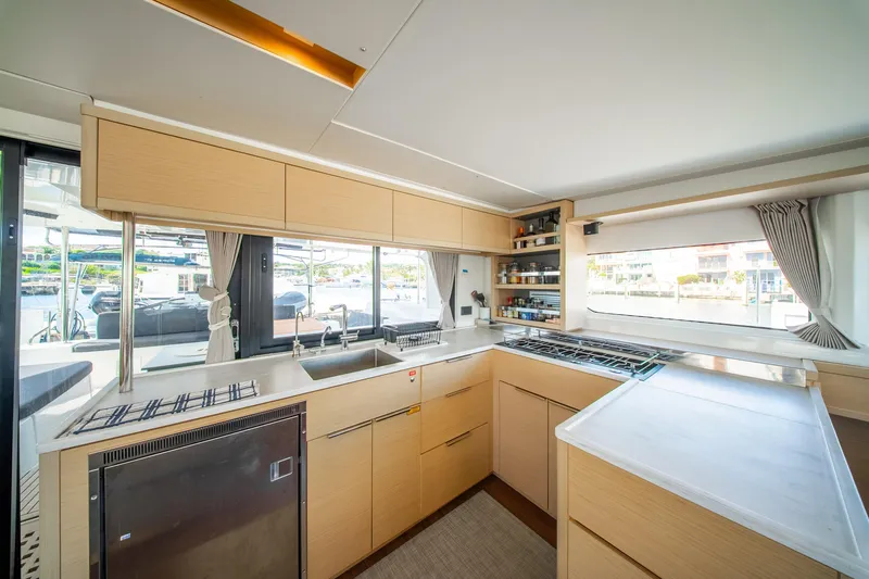 Dakiti Yacht Photos Pics Modern kitchen interior of 2023 Lagoon 46 yacht with sleek cabinetry and large windows.