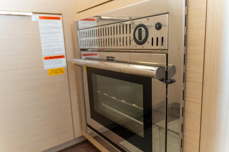 Dakiti Yacht Photos Pics Modern oven in 2023 Lagoon 46 yacht kitchen, featuring stainless steel design and control panel.