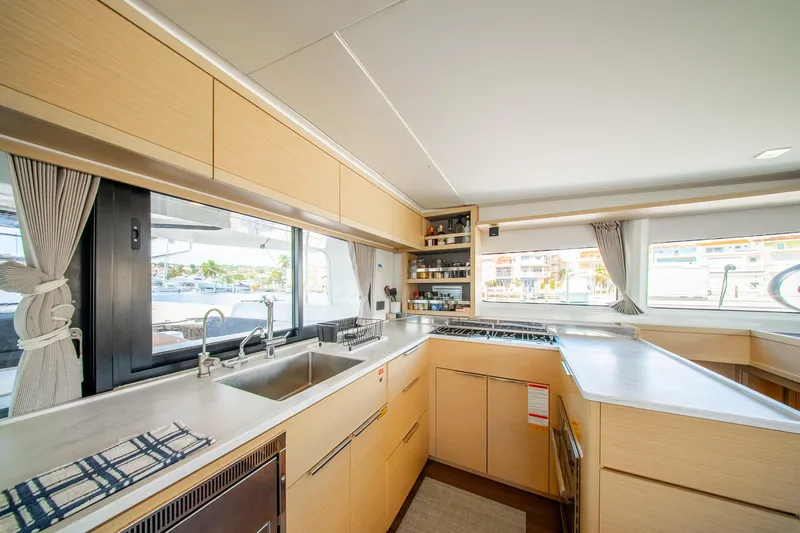 Dakiti Yacht Photos Pics Modern kitchen interior of 2023 Lagoon 46 catamaran with sleek cabinetry and large windows.