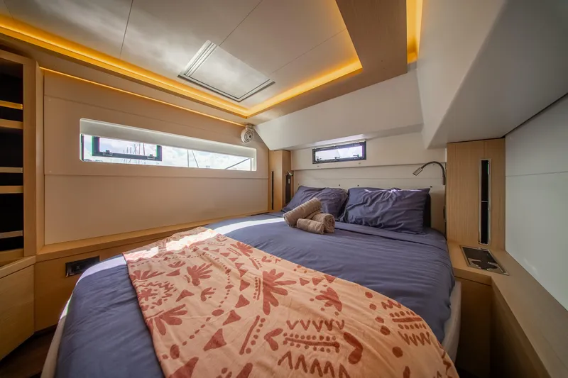 Dakiti Yacht Photos Pics Luxurious bedroom interior of 2023 Lagoon 46 yacht with modern design and ambient lighting.