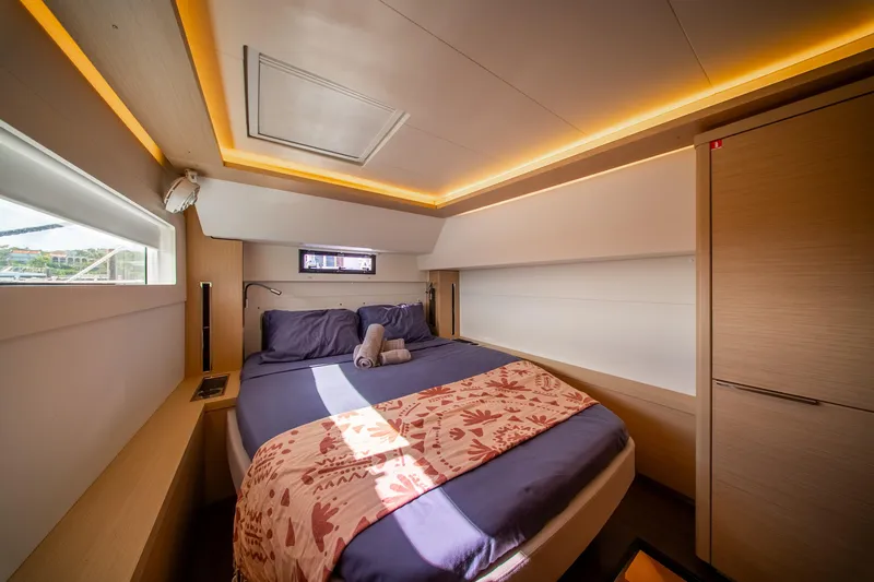 Dakiti Yacht Photos Pics Luxurious cabin interior of 2023 Lagoon 46 yacht with modern lighting and cozy bedding.