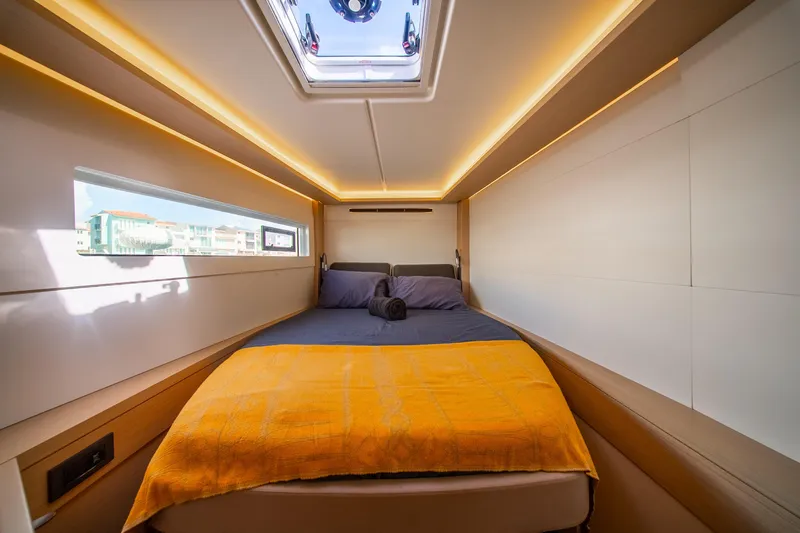 Dakiti Yacht Photos Pics Luxurious cabin interior of 2023 Lagoon 46 yacht with modern lighting and cozy bedding.