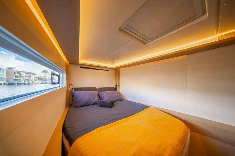 Dakiti Yacht Photos Pics Luxurious cabin interior of 2023 Lagoon 46 yacht with cozy bedding and ambient lighting.