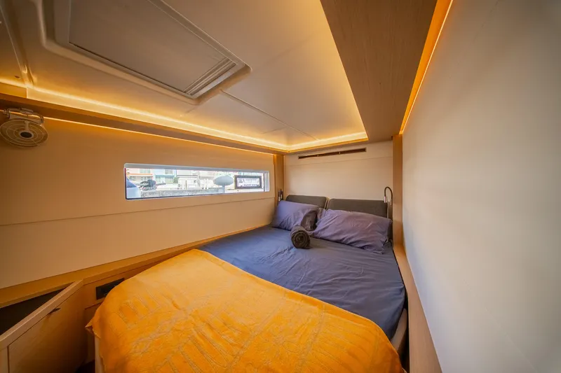 Dakiti Yacht Photos Pics Luxurious cabin interior of 2023 Lagoon 46 yacht with cozy bedding and ambient lighting.