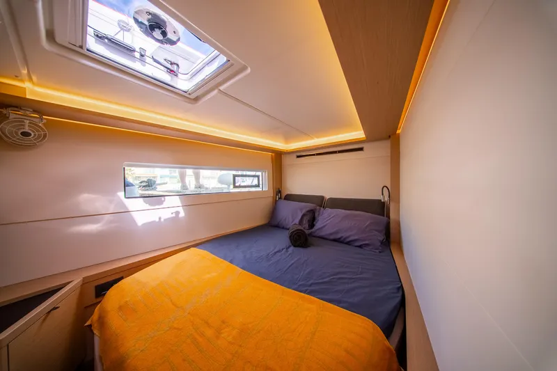 Dakiti Yacht Photos Pics Luxurious cabin interior of 2023 Lagoon 46 yacht with cozy bedding and ambient lighting.