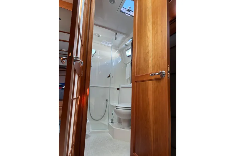  Yacht Photos Pics 2023 Sabre 45 Salon Express bathroom interior with wooden door and modern fixtures.