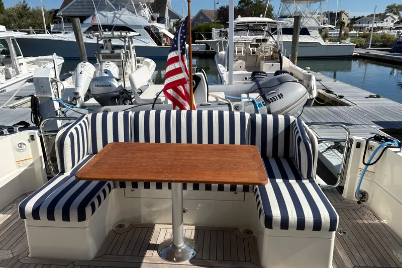  Yacht Photos Pics 2023 Sabre 45 Salon Express yacht with striped seating and wooden table at marina.