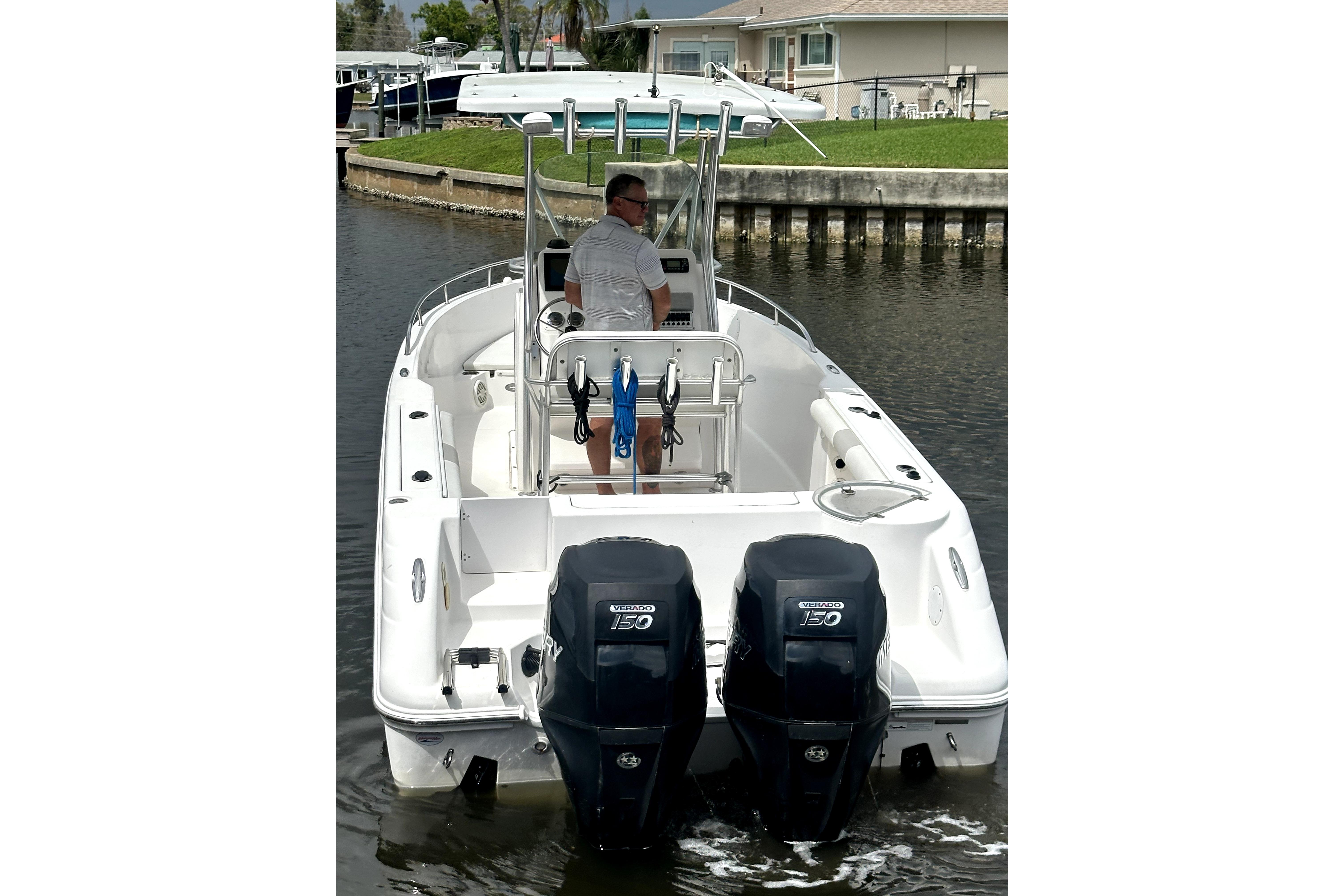 2014 Pro-Line 26 Super Sport boat with dual outboard engines on a calm waterway.