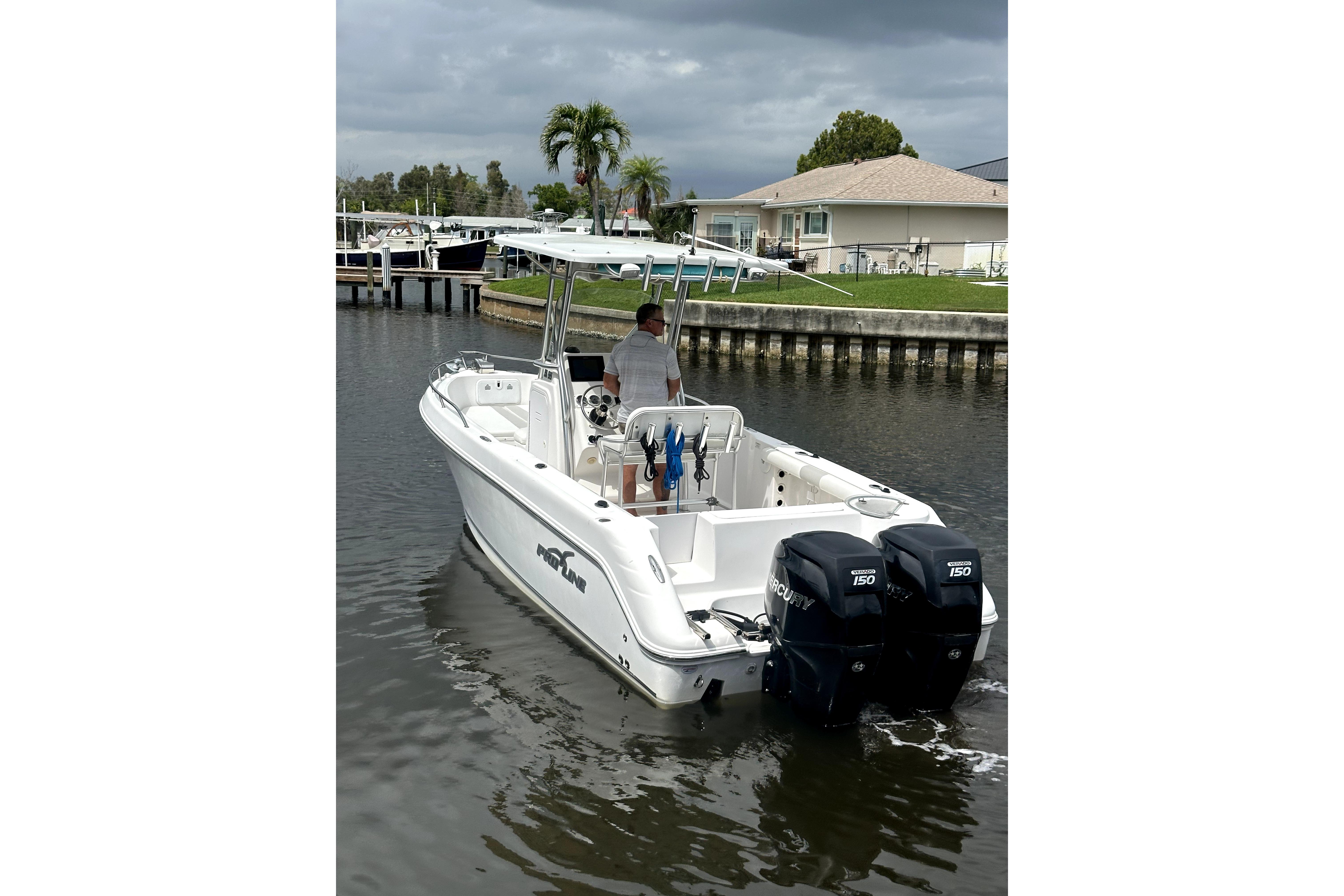 2014 Pro-Line 26 Super Sport boat with dual Mercury engines on a calm waterway.