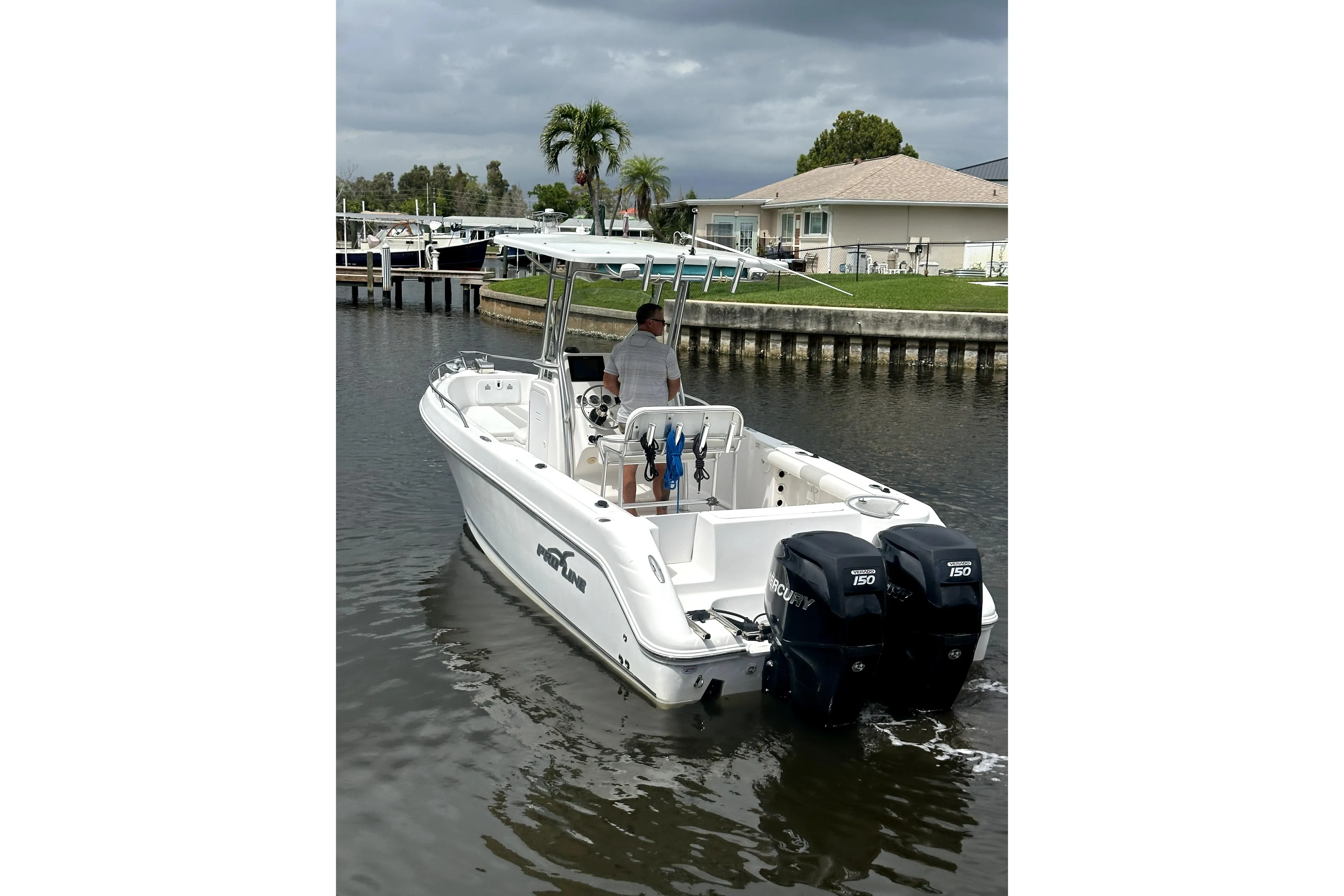 2014 Pro-Line 26 Super Sport boat with dual Mercury engines on a calm waterway.