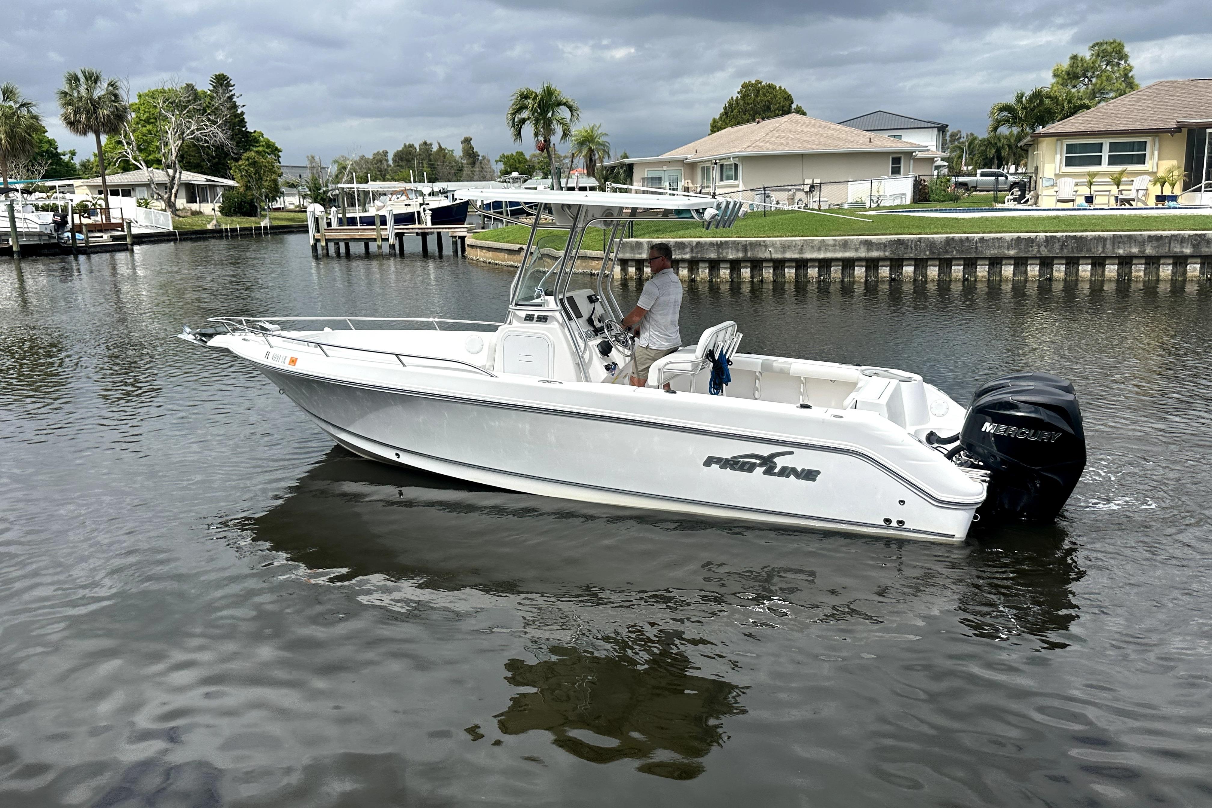 2014 Pro-Line 26 Super Sport boat cruising on a calm residential canal.