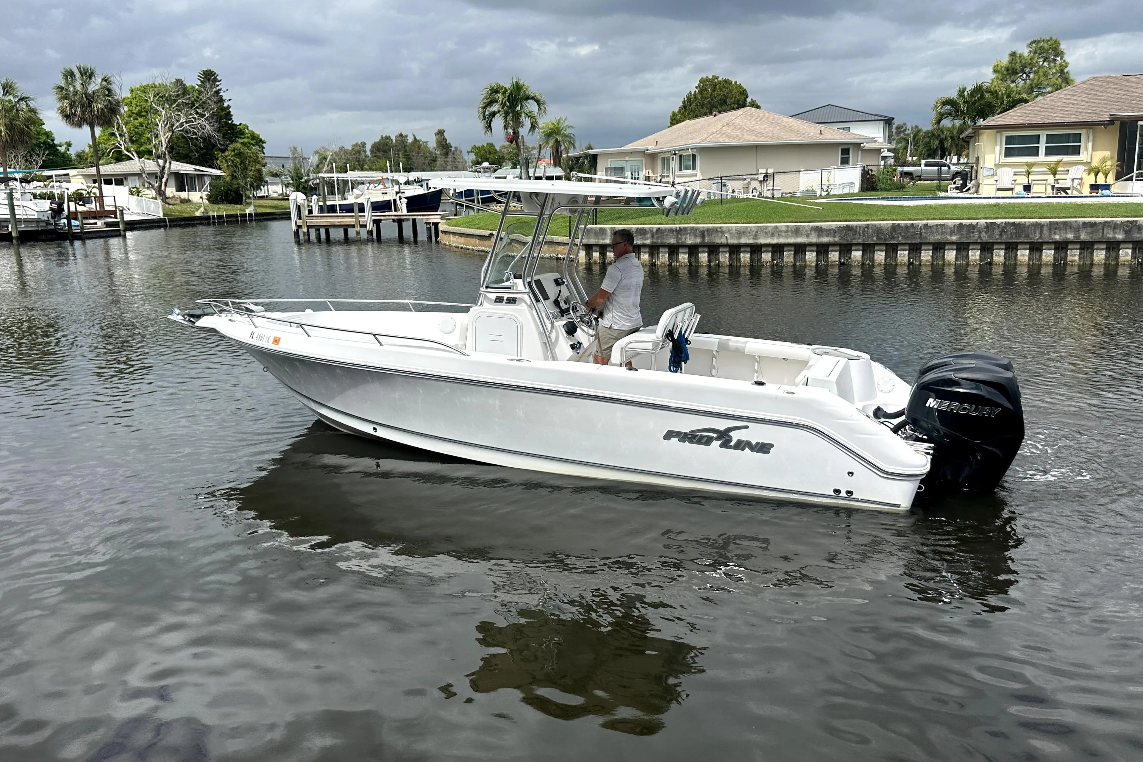2014 Pro-Line 26 Super Sport boat cruising on a calm residential canal.