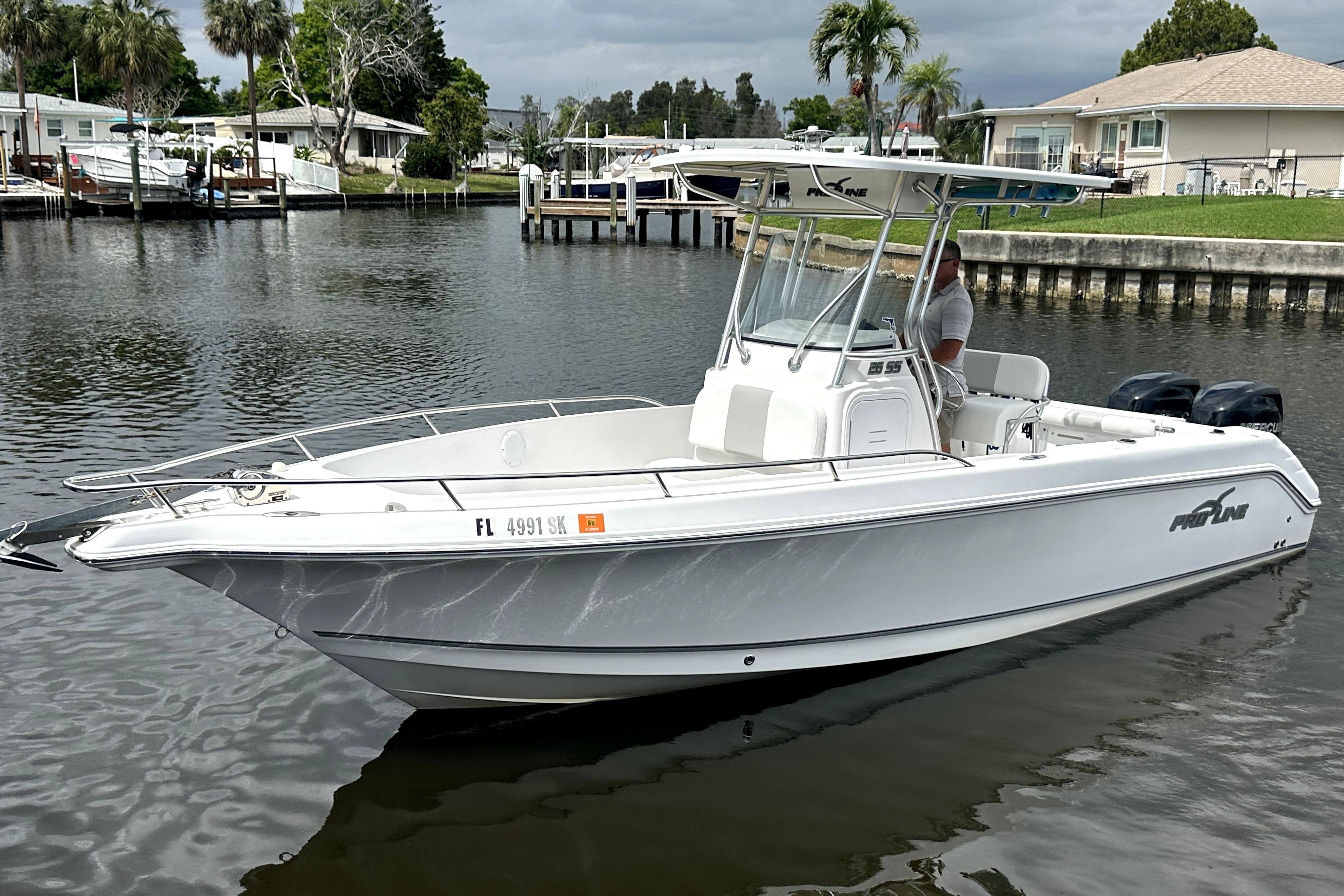 2014 Pro-Line 26 Super Sport boat on calm water, dockside view.