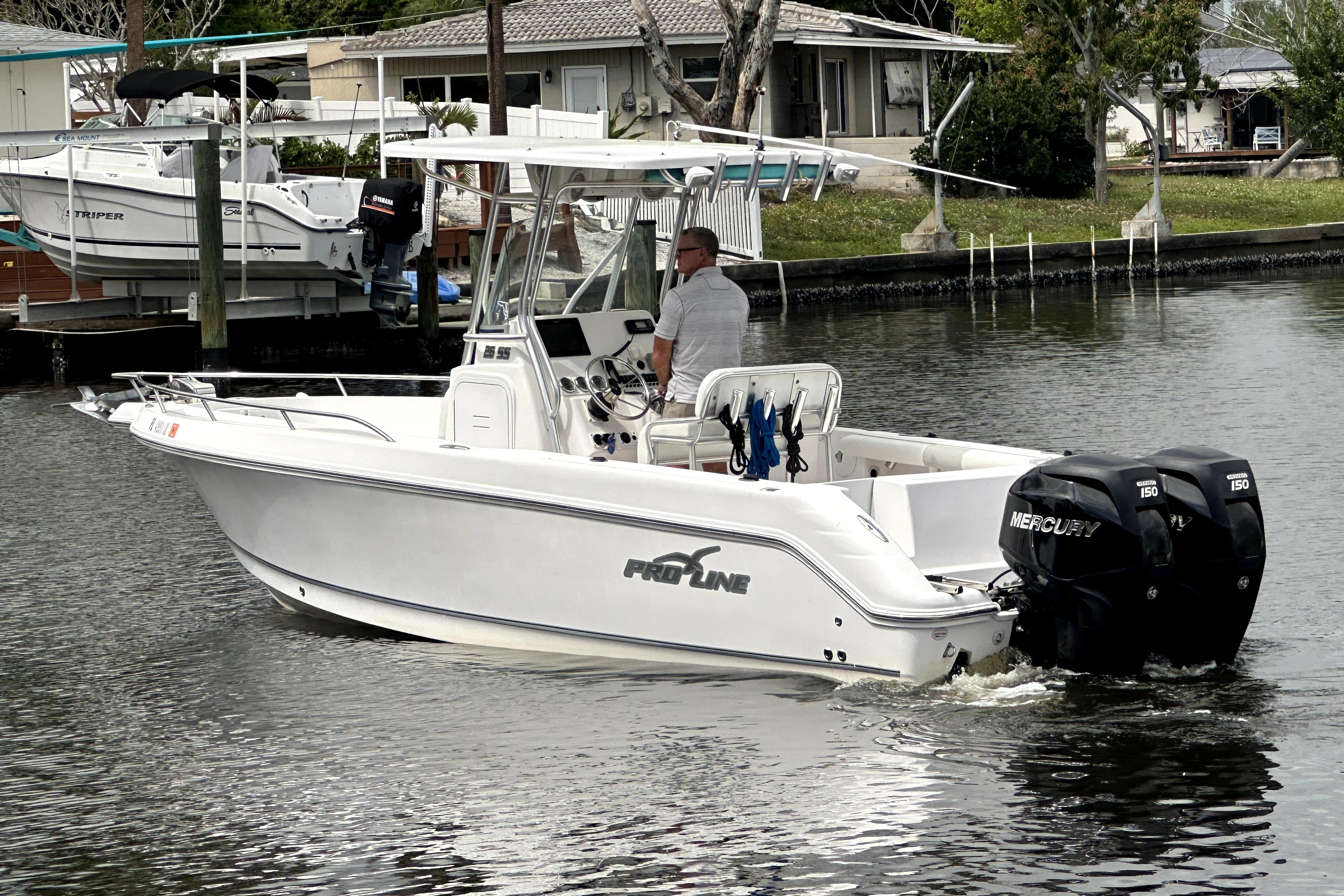 2014 Pro-Line 26 Super Sport boat with dual Mercury engines on a calm waterway.