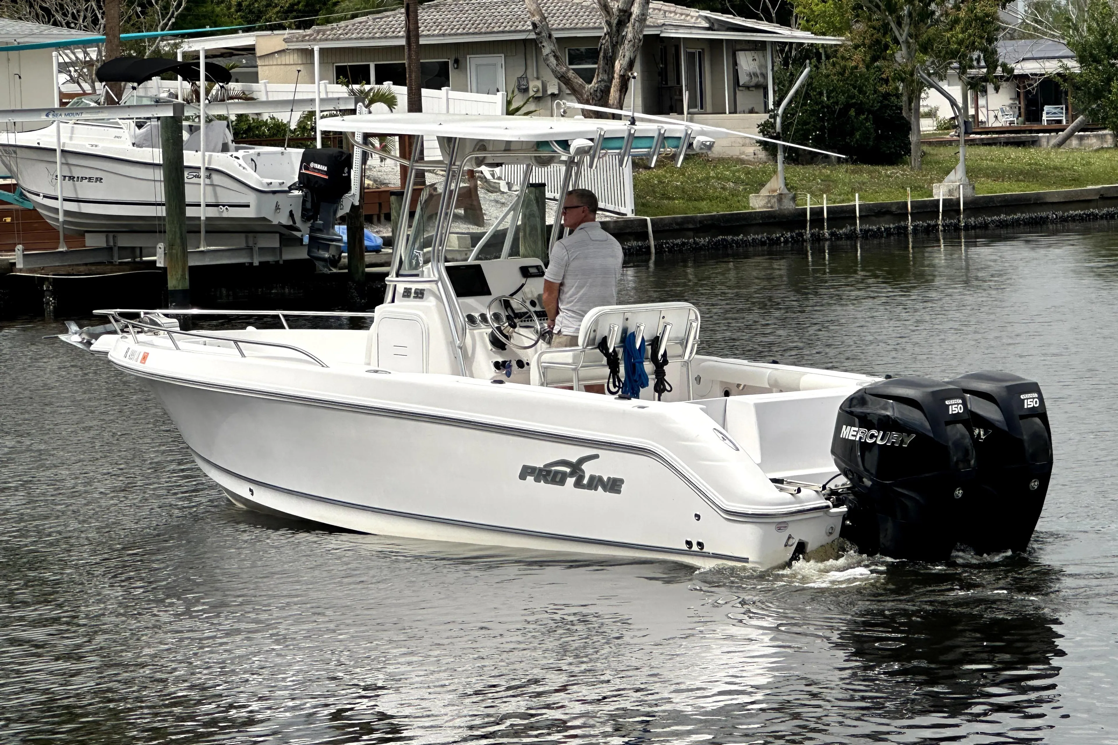 2014 Pro-Line 26 Super Sport boat with dual Mercury engines on a calm waterway.