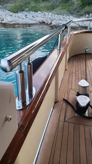 Korab Yacht Photos Pics Custom Motor Yacht Korab deck with polished railings, docked by clear turquoise water.