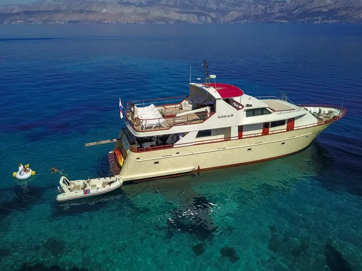 Korab Yacht Photos Pics Custom Motor Yacht Korab, 2001, anchored in clear blue waters with inflatable swan nearby.