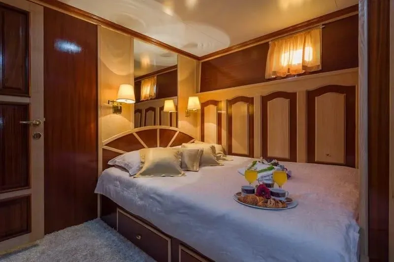 Korab Yacht Photos Pics Luxurious bedroom on Motor Yacht Korab, 2001, featuring elegant wood paneling and cozy lighting.