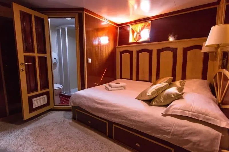 Korab Yacht Photos Pics Luxurious bedroom on Motor Yacht Korab, 2001, featuring elegant wood paneling and en-suite bathroom.