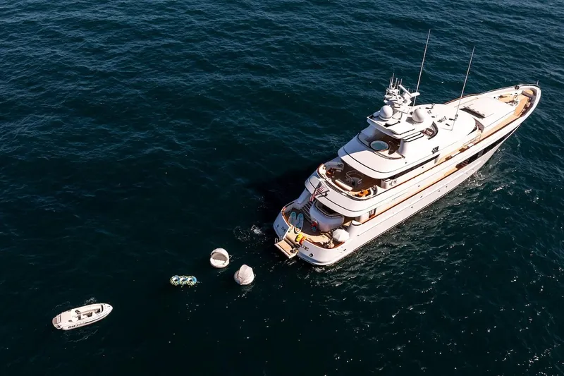 Mystique Yacht Photos Pics Luxurious 2001 Feadship Custom yacht on open sea with small boats nearby.