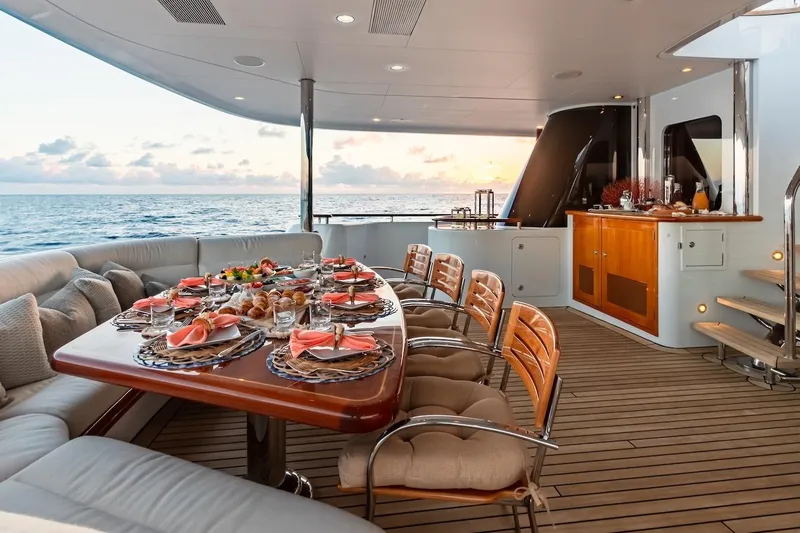 Mystique Yacht Photos Pics Luxurious dining setup on 2001 Feadship Custom yacht, ocean view at sunset.
