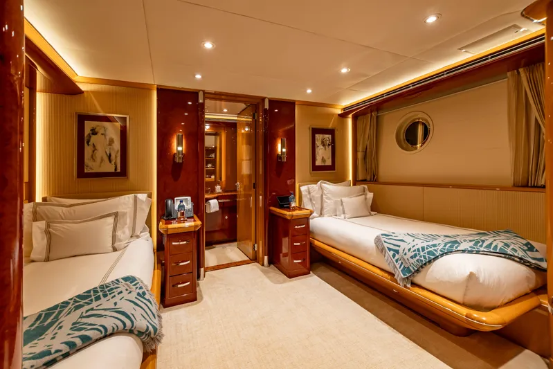 Mystique Yacht Photos Pics Luxurious twin cabin on 2001 Feadship Custom yacht, featuring elegant wood finishes and cozy bedding.