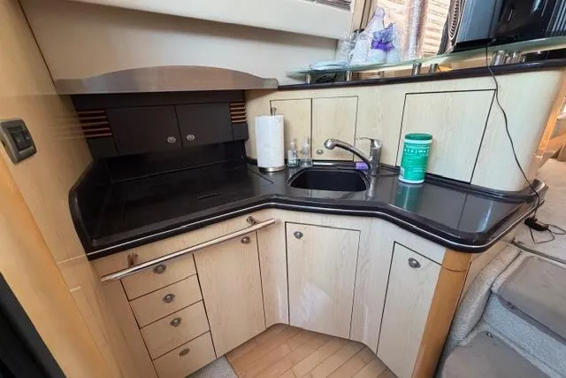 Big Energy Yacht Photos Pics 2004 Sea Ray 420 Sedan Bridge kitchen with sleek black countertops and modern cabinetry.