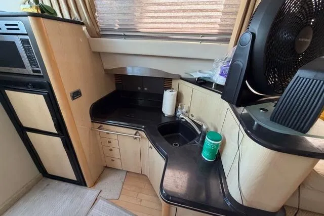 Big Energy Yacht Photos Pics 2004 Sea Ray 420 Sedan Bridge kitchen with black countertops and modern appliances.