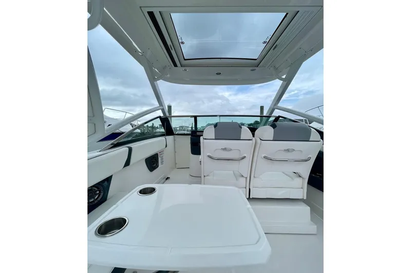 Seaventure Yacht Photos Pics 2023 Chaparral 280 OSX boat interior with white seating and table, featuring a sunroof.