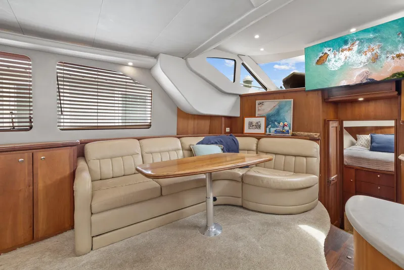 Sunset Chaser Yacht Photos Pics Interior of 2002 Silverton 43 Motor Yacht with beige seating and wooden table.