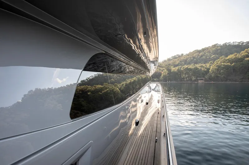  Yacht Photos Pics Side view of 2009 Canados 110 yacht reflecting serene water and lush greenery.