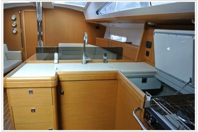  Yacht Photos Pics Interior of 2010 Jeanneau Sun Odyssey 42 DS yacht, featuring modern kitchen and sleek wood finish.