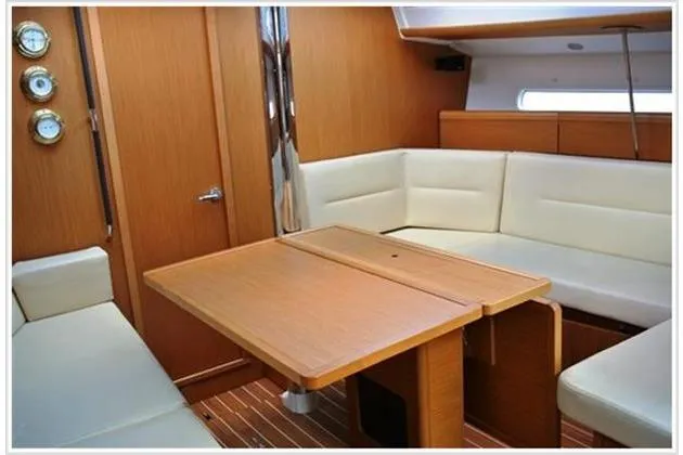  Yacht Photos Pics Interior of 2010 Jeanneau Sun Odyssey 42 DS with wooden table and white seating.