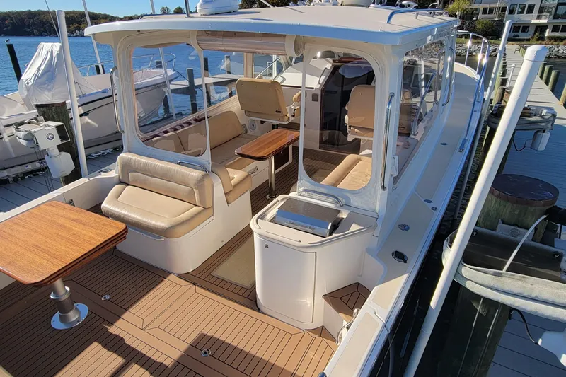 Captivator Yacht Photos Pics 2017 MJM 40z Downeast yacht with elegant seating and wooden tables docked by the water.