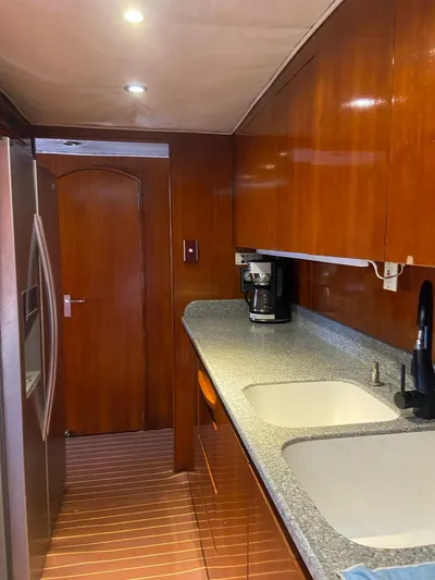 New Beginning Yacht Photos Pics Galley kitchen in 1990 Cheoy Lee 75 yacht with wood cabinetry and modern appliances.